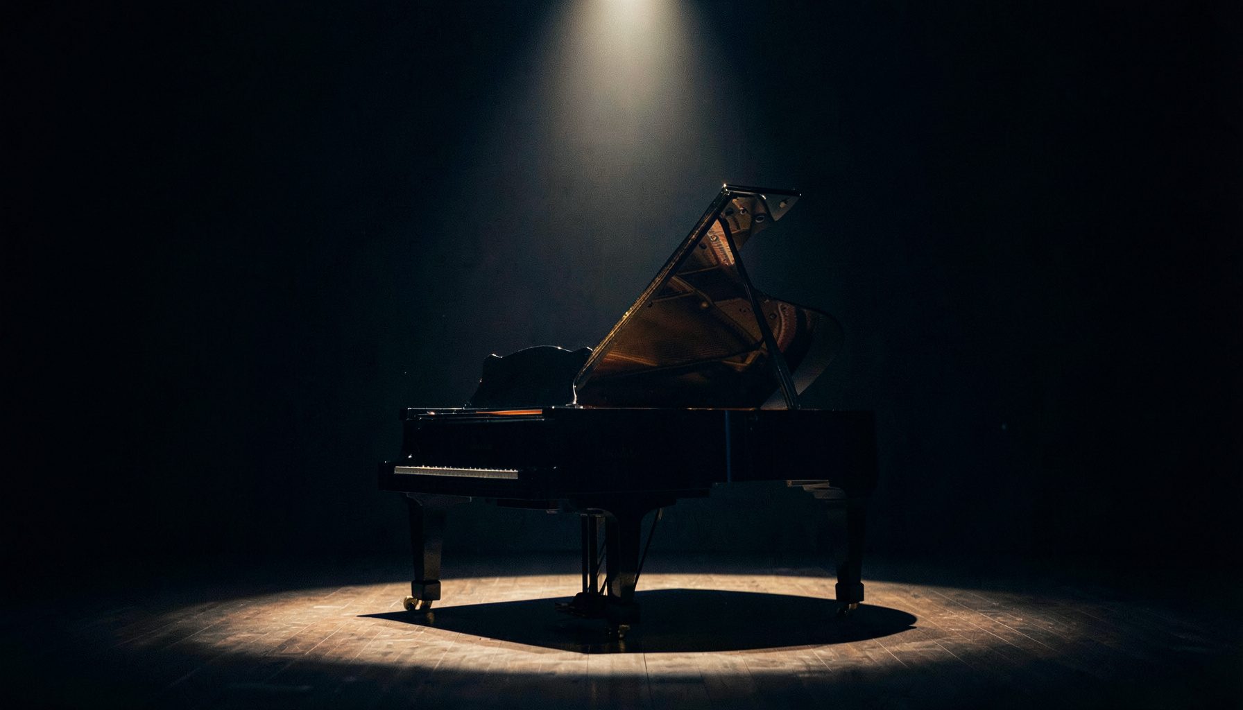 Grand piano on a darkened stage lit by a single overhead spotlight
