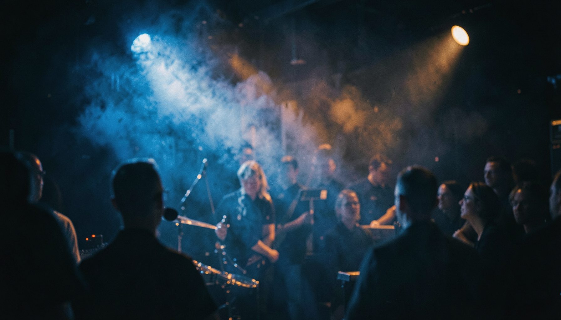 Warm amber stage lights glowing through blue haze in a dim jazz club