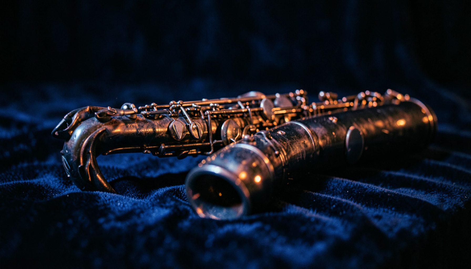 Saxophone resting on a velvet surface with moody indigo and copper lighting