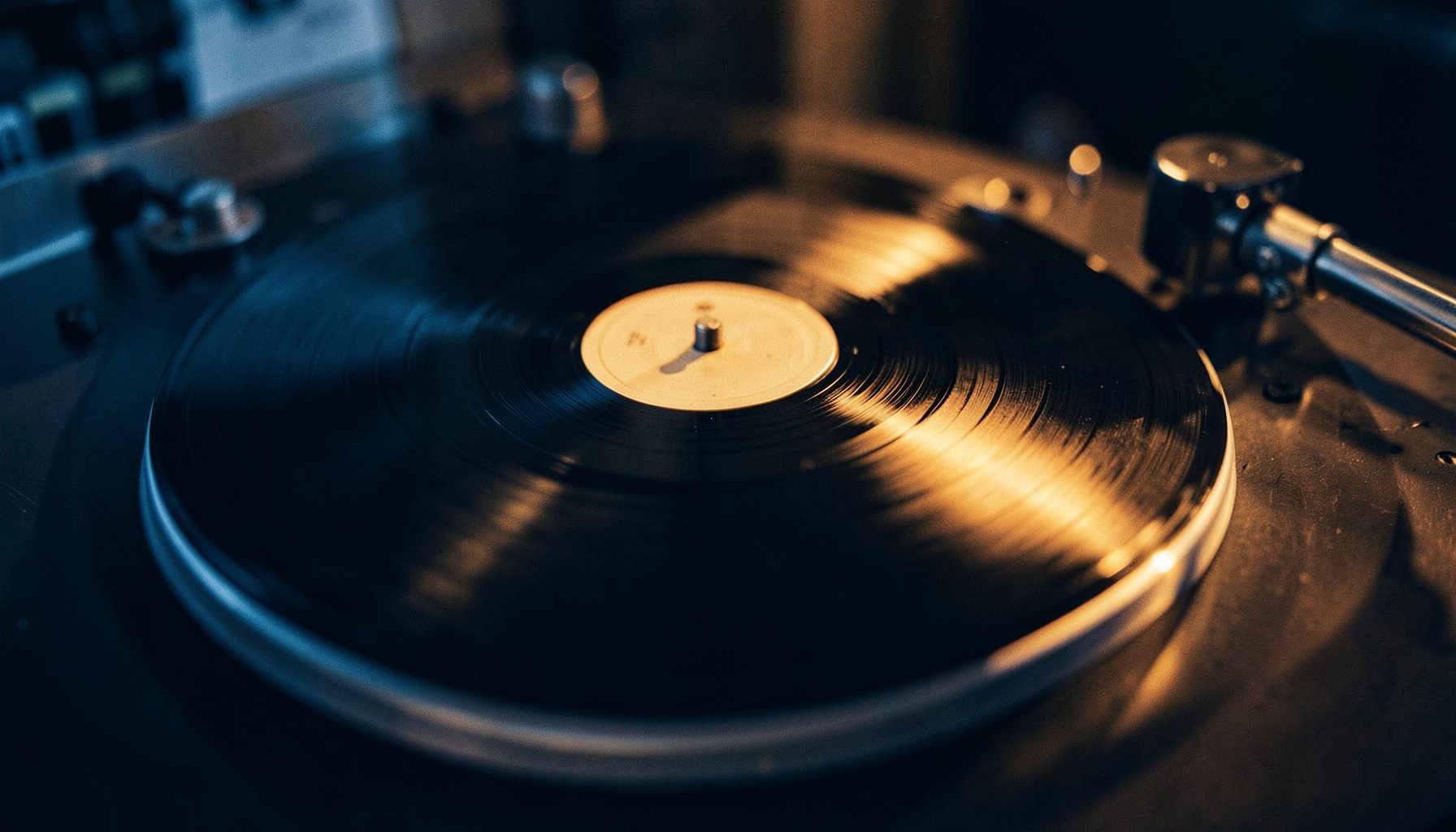 Vinyl record spinning on a turntable with warm amber light and deep shadows across the platter